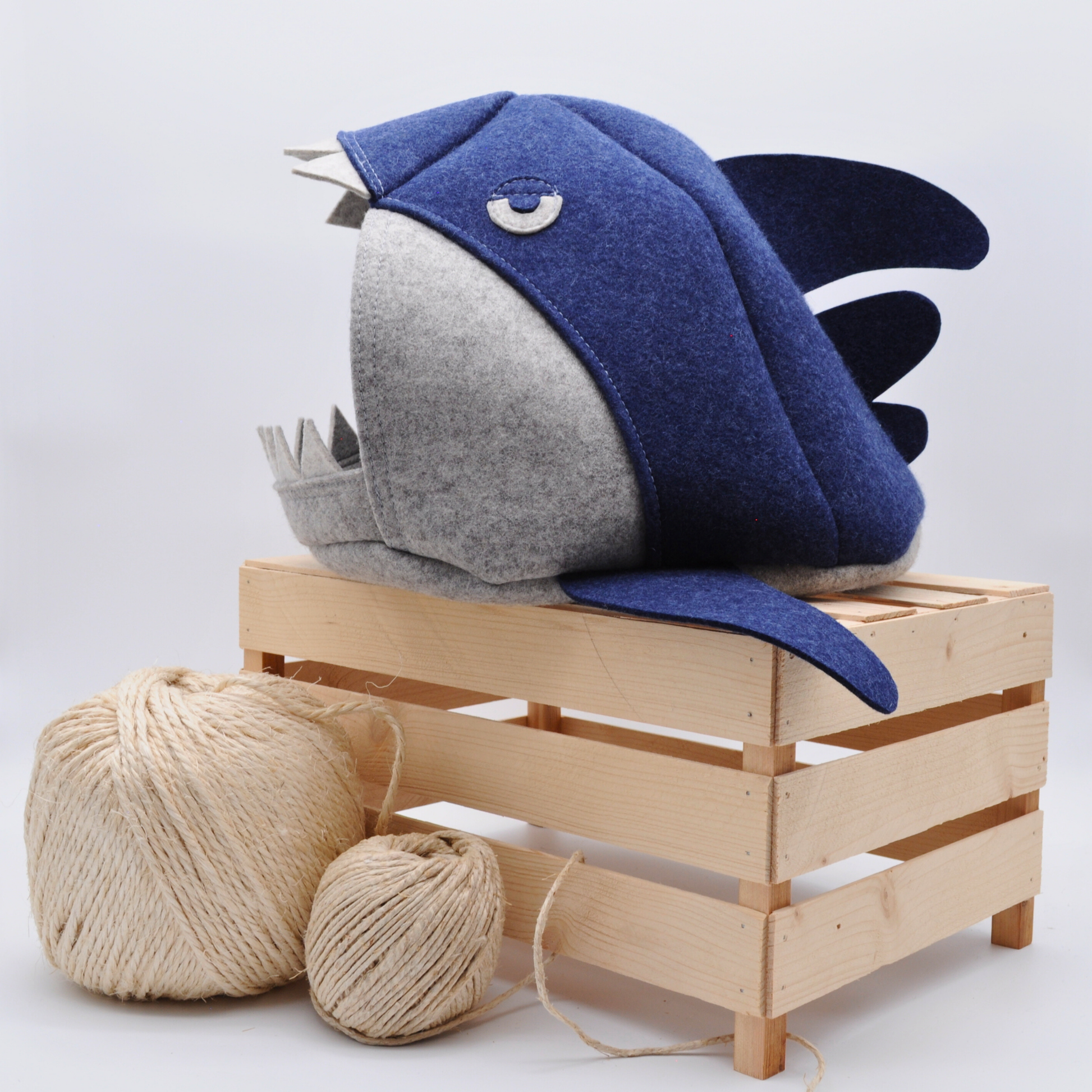 Grau-blaue Katzenhöhle im Makohai-Stil, auf Holzkiste präsentiert mit platziert mit Sisalball im Vordergrund – natürliche Wohnatmosphäre