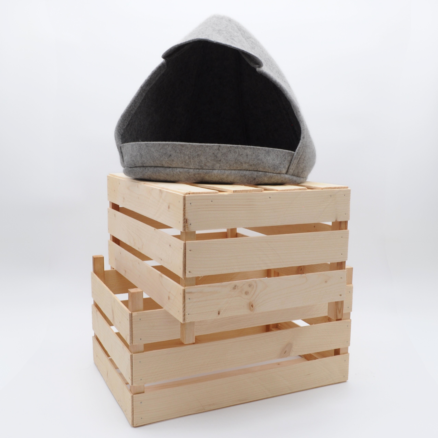 Minimalistische graue Katzenhöhle aus Wollfilz, auf gestapelten Holzkisten schafft stilvolle Wohnatmosphäre