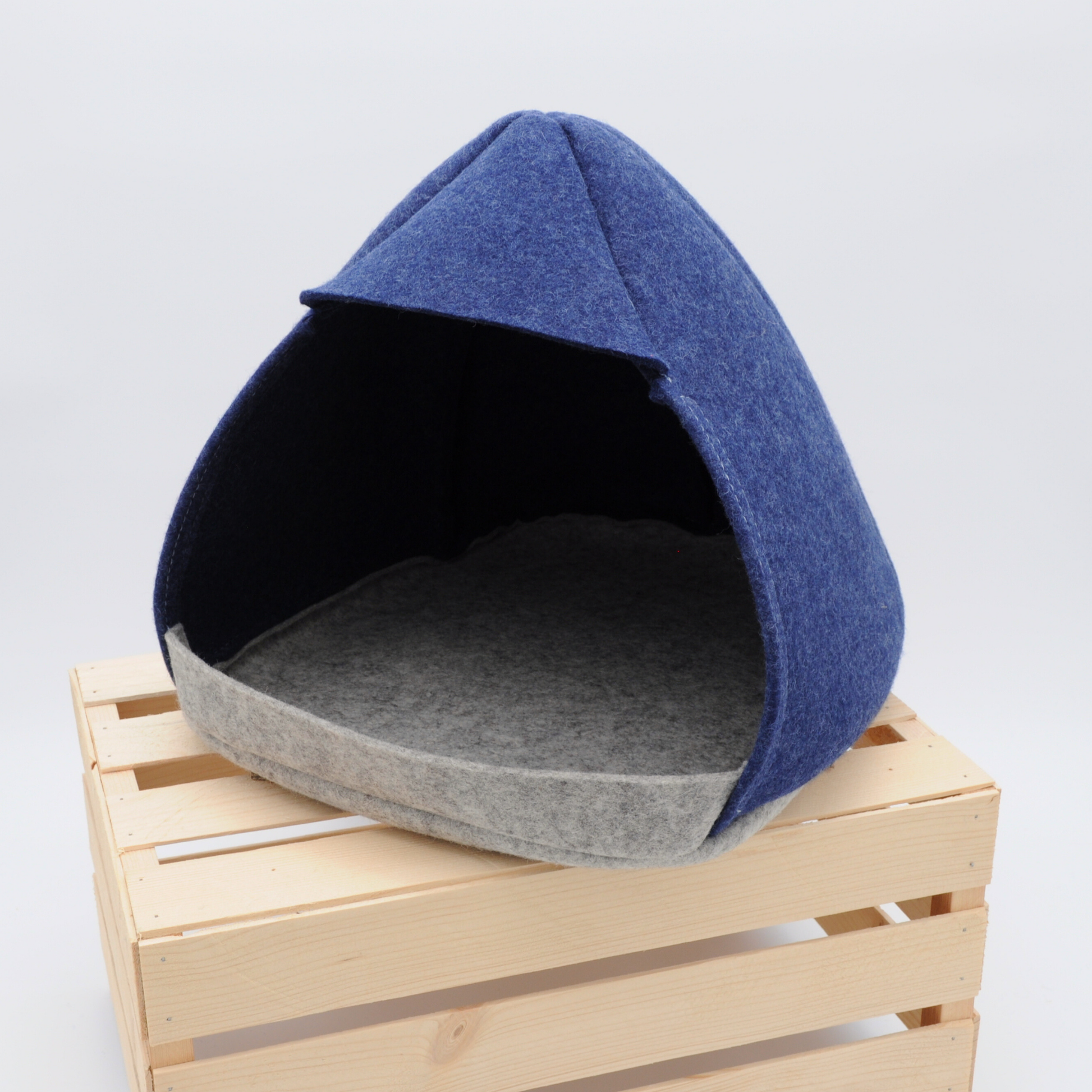 Zweifarbige Filz-Katzenhöhle in Grau und Indigo, 45-Grad-Ansicht auf Holzkiste