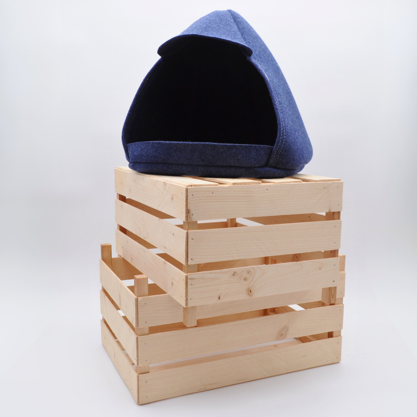 Indigo-blaue Katzenhöhle in klarer Formensprache, auf Holzkisten schafft stilvolle Wohnatmosphäre