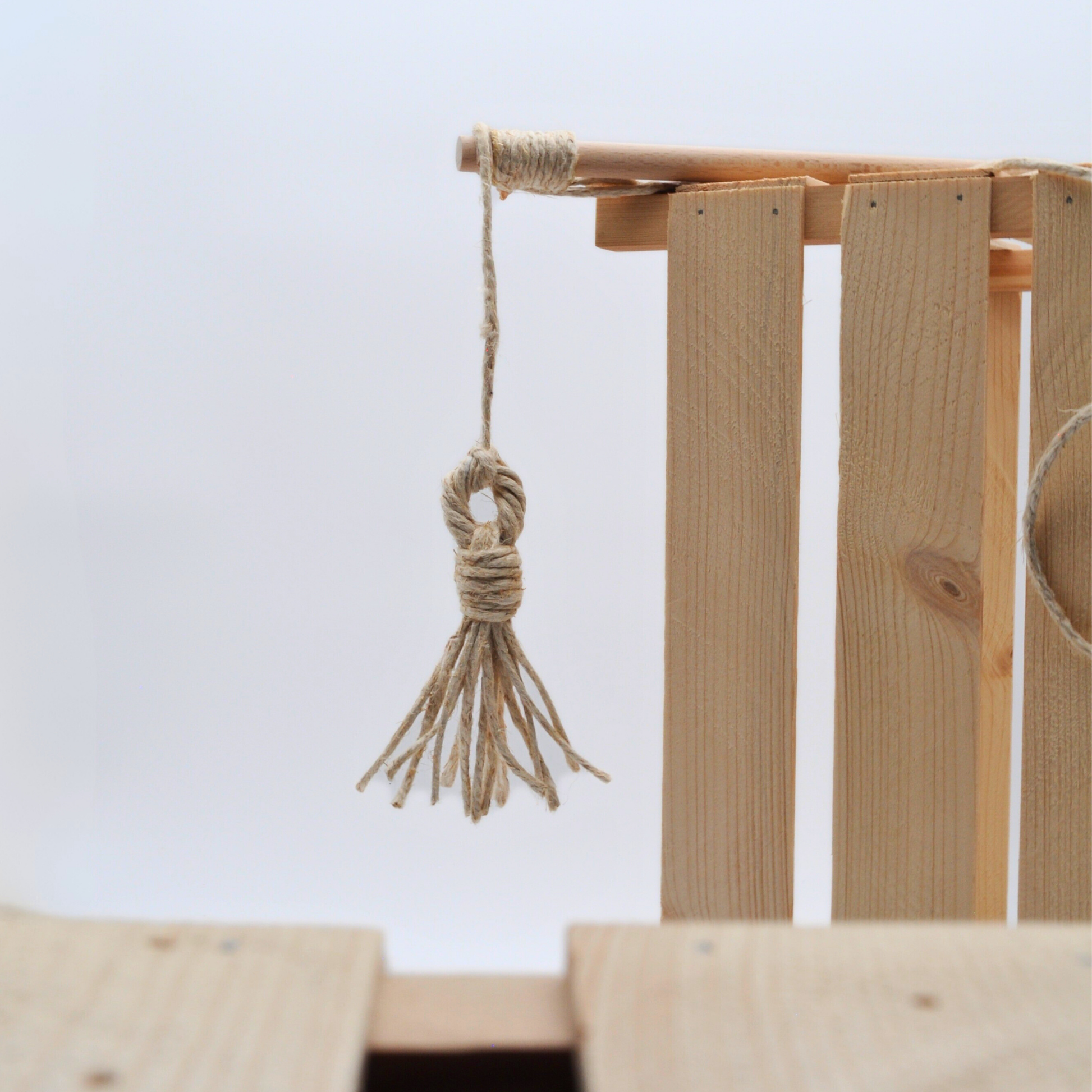 Anhänger der Katzenangel „Wildfang“ hängt von Holzkiste herab, unscharfer Hintergrund