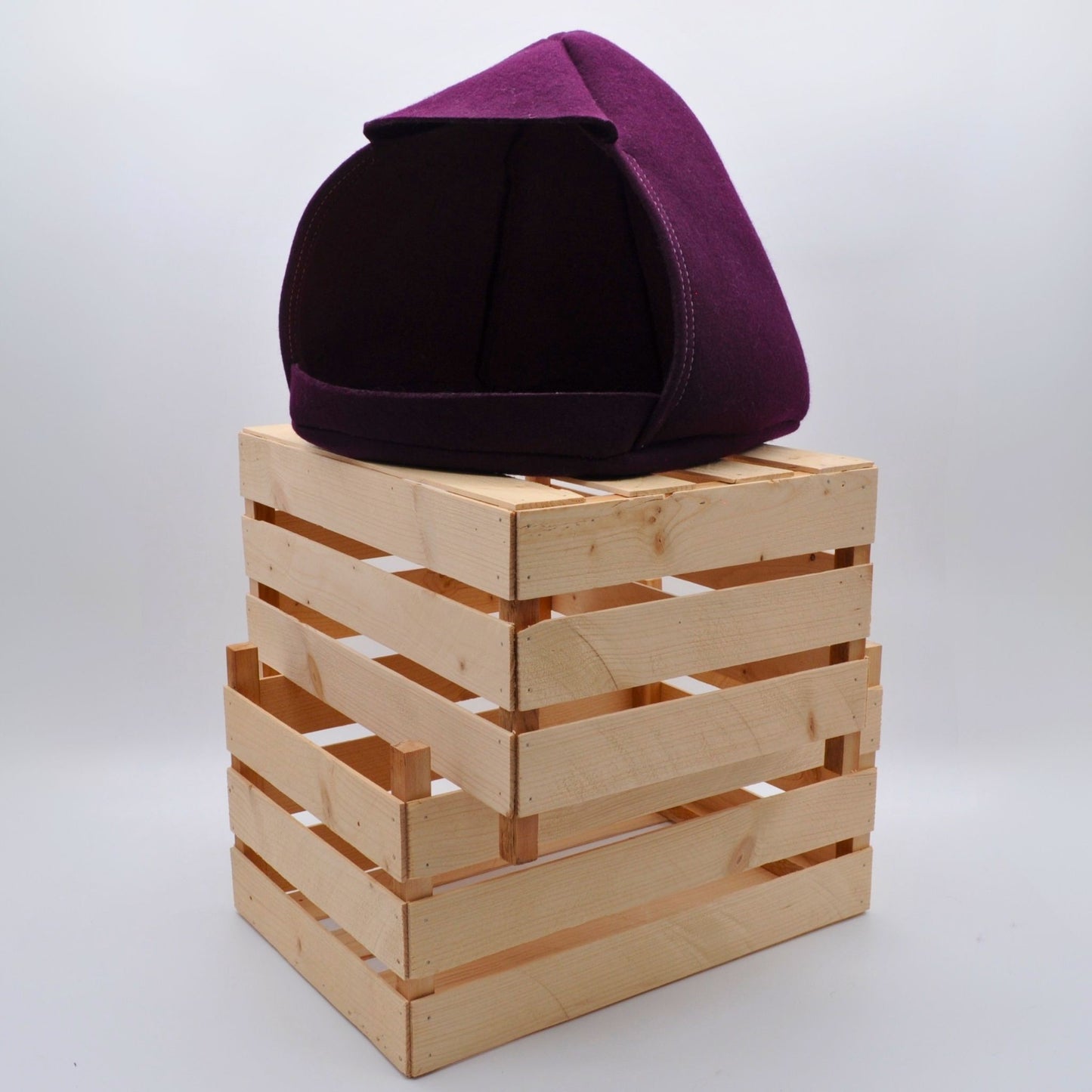 Aubergine-farbene Katzenhöhle in klarer Formensprache, auf Holzkisten schafft stilvolle Wohnatmosphäre