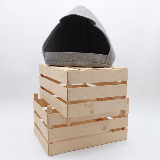 Minimalistische graue Katzenhöhle aus Wollfilz, auf gestapelten Holzkisten schafft stilvolle Wohnatmosphäre