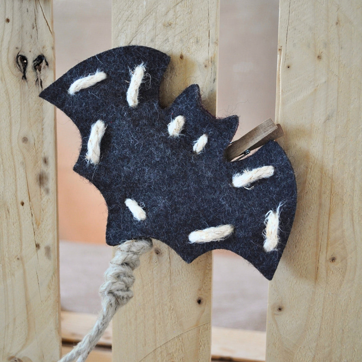 Pfotenwerk Fledermaus aus anthrazitfarbenem Wollfilz hängt an einer Holzkiste