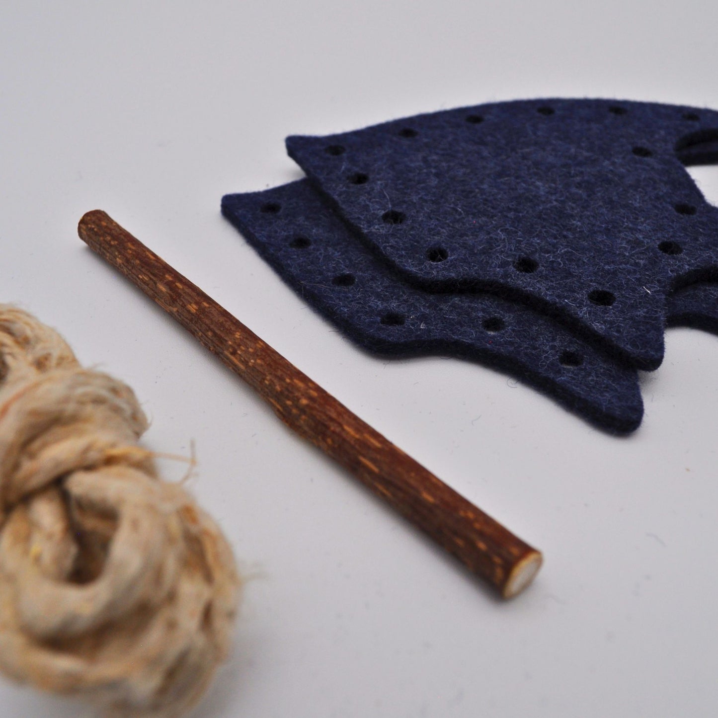 Einzelteile des DIY-Katzenspielzeugs Pfotenwerk Ozean-Edition „Skalar“: zwei Filzlagen in Dunkelblau, Hanfschnur und Matatabi-Stab
