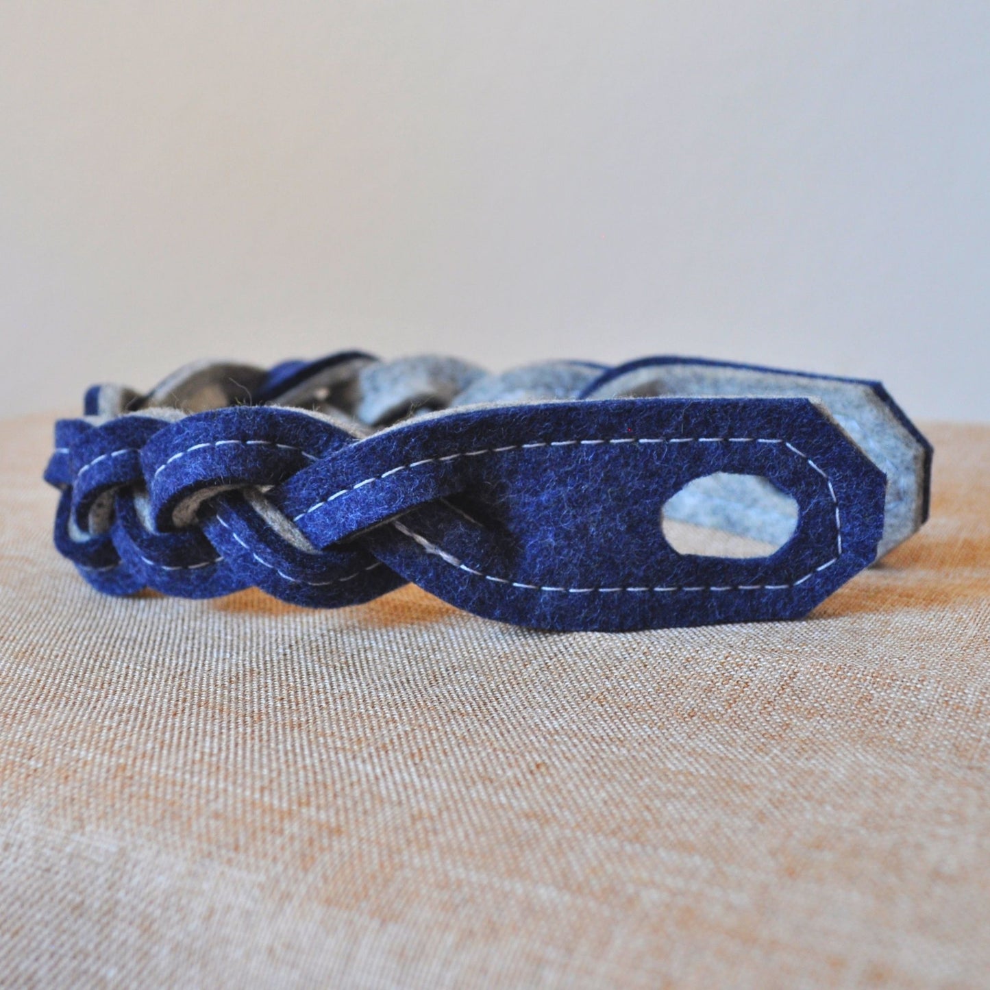 Türwächter aus Merino-Wollfilz in Indigo, gebogene Form mit hellgrauer Rückseite auf beigem Leinenstoff